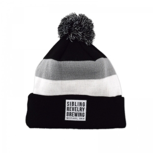 Sibling Revelry pom beanie with woven label patch.